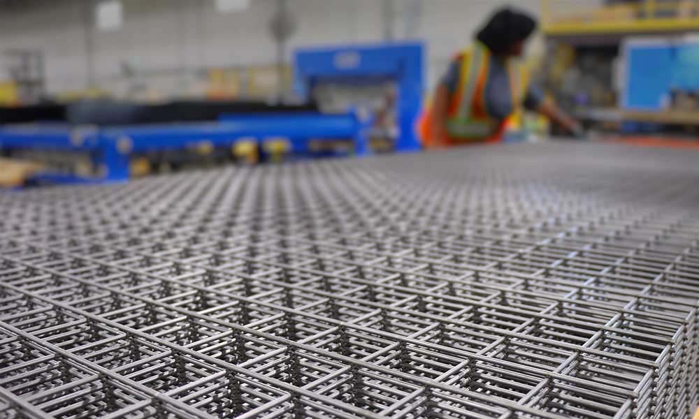 worker looking over a stack of wire mesh